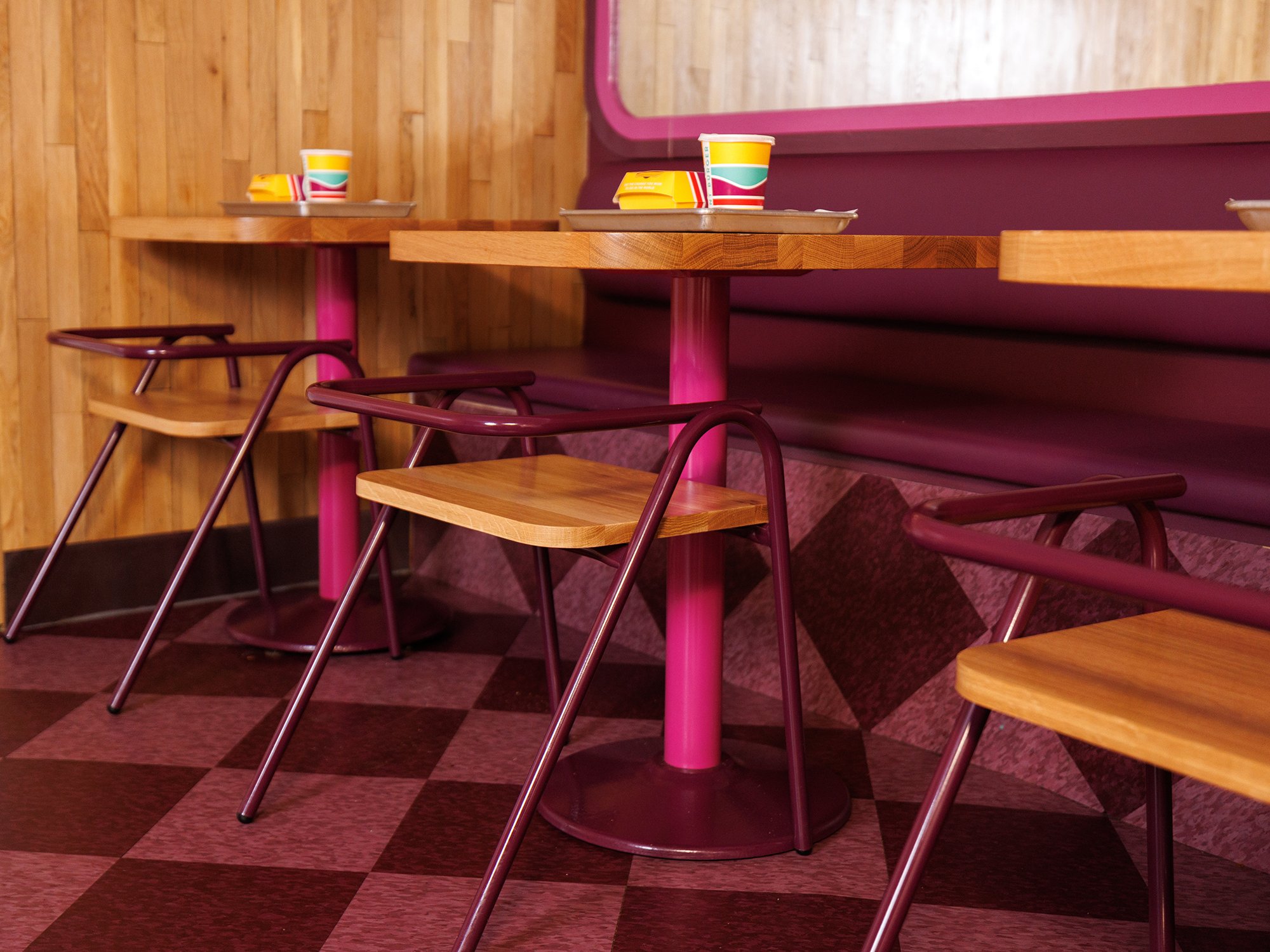 Restaurant scene with magenta checkered floors and tables and natural food finishes. 
