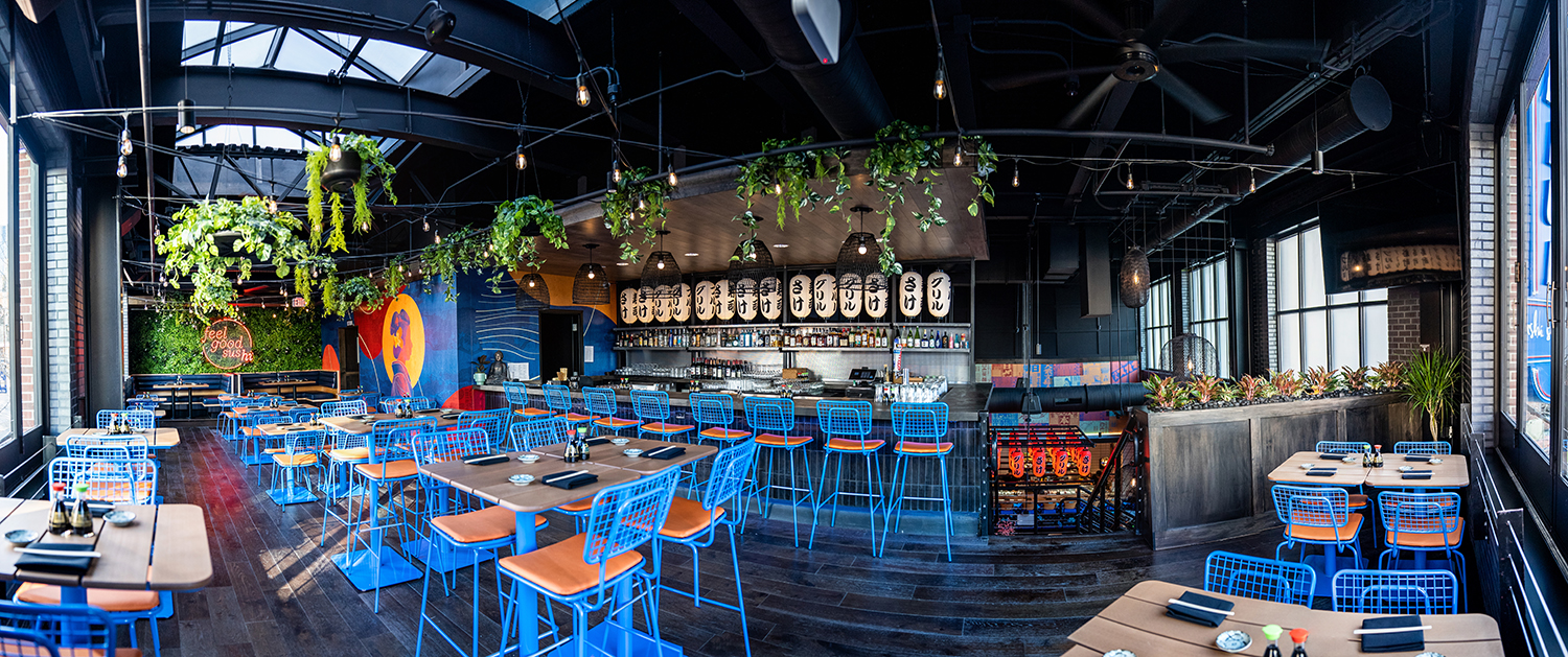 Panoramic view of a restaurant interior with blue opla chairs and bowen tables. 